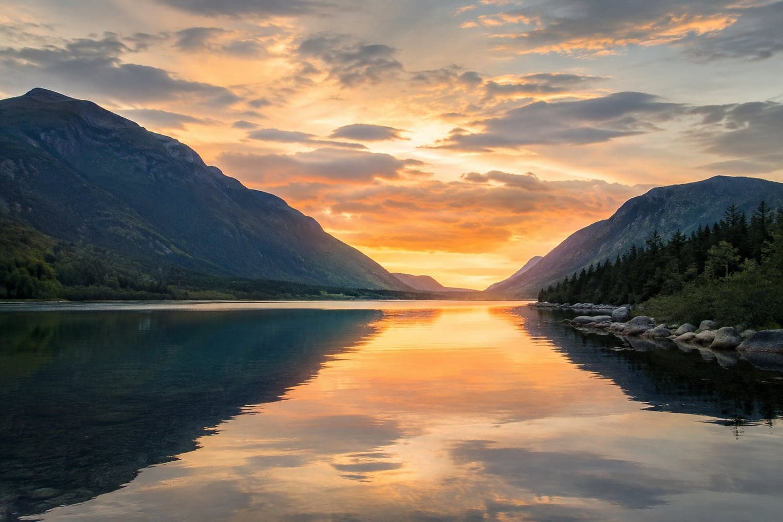 A still lake between two mountain ridges at sunset, the whole sky held perfectly in the water